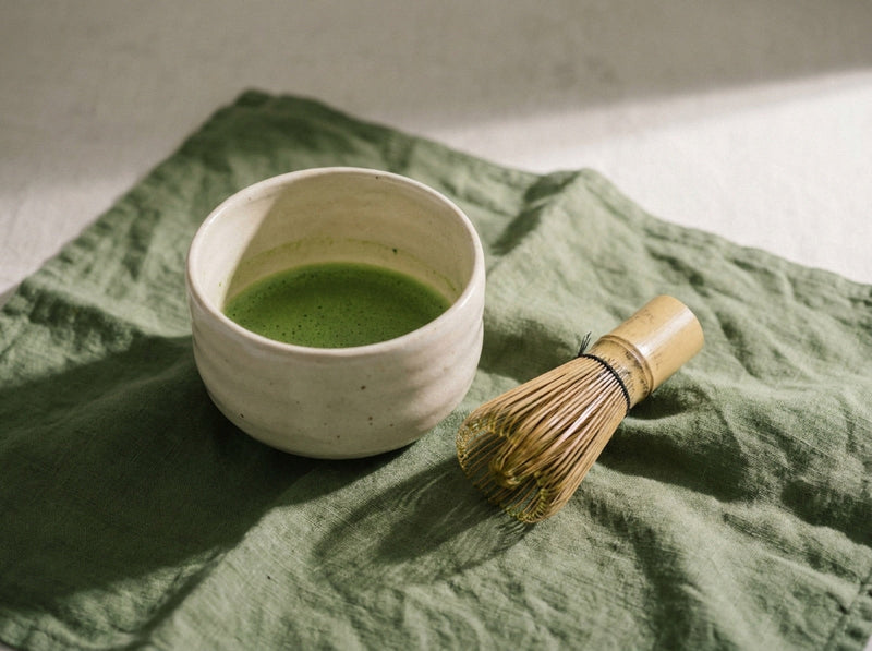 A bowl of whisked usucha beside a bamboo chasen